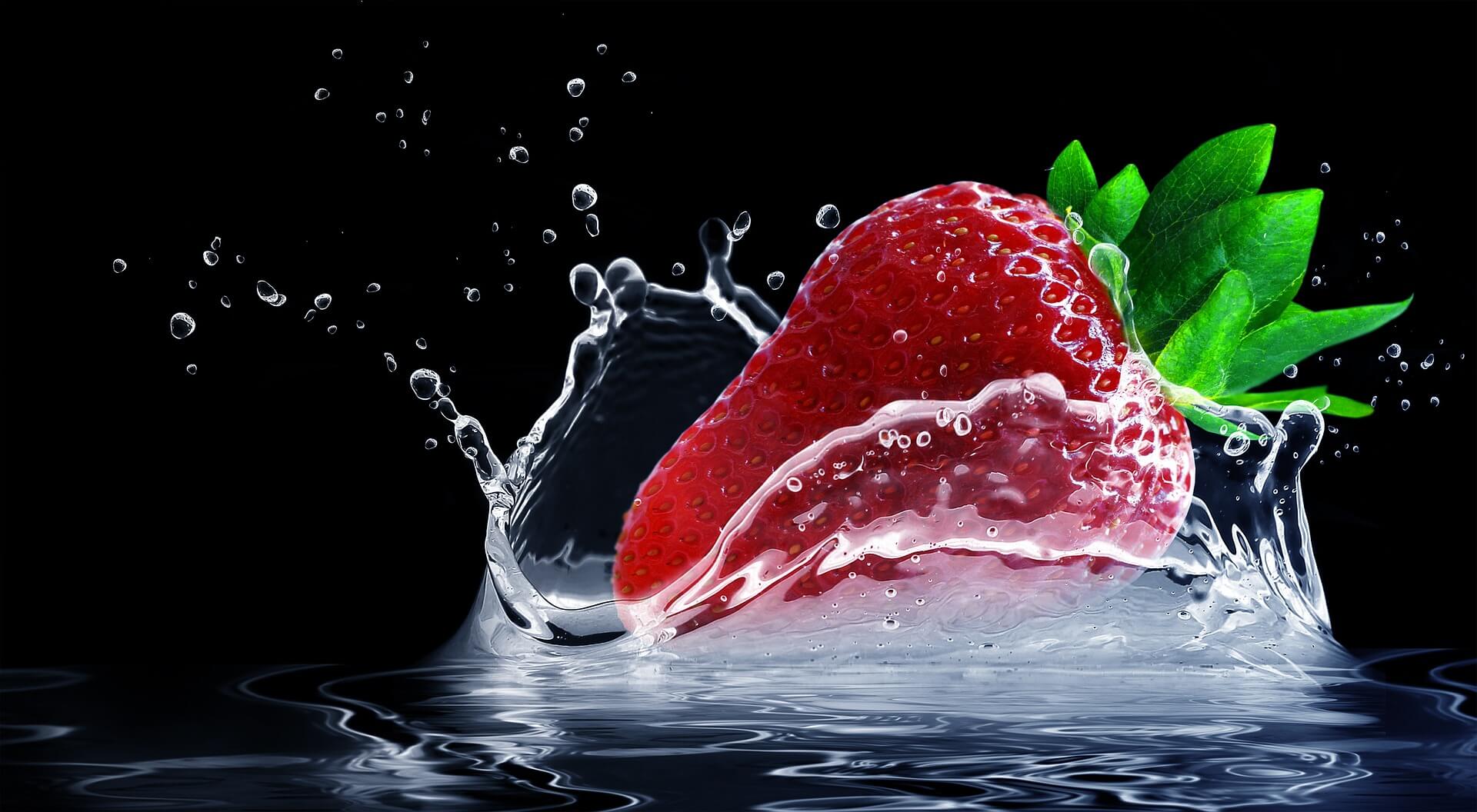 fresa cayendo sobre agua y con un fondo negro