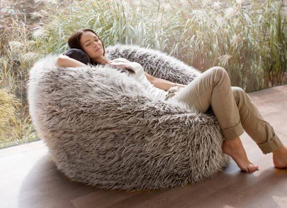 woman laying on a beige furry beanbag