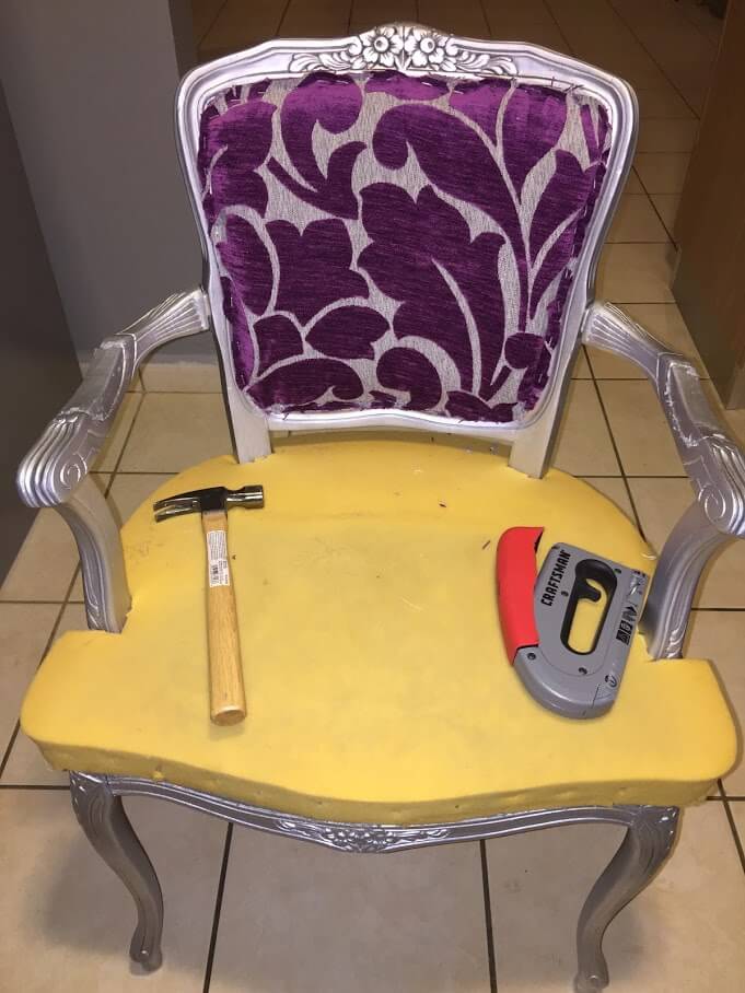 small victorian arm chair with a hammer and stapler on top if it
