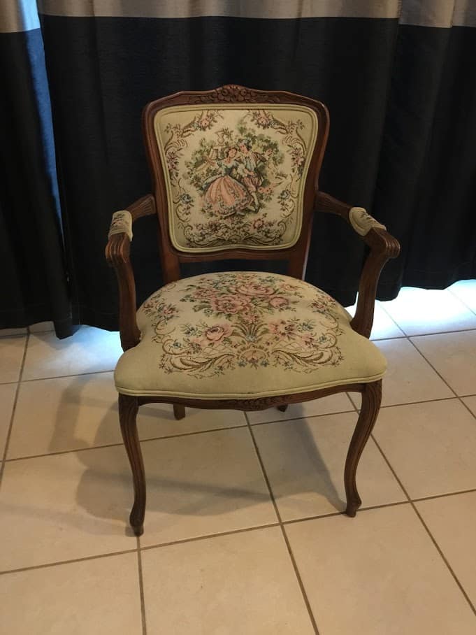 small victorian arm chair in front of a black curtain