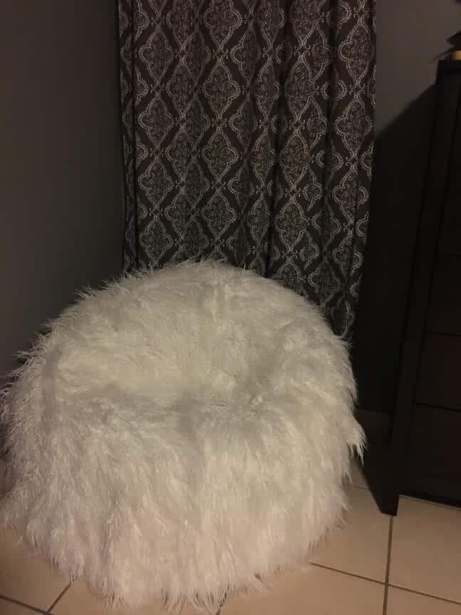 white furry bean bag behind a curtain