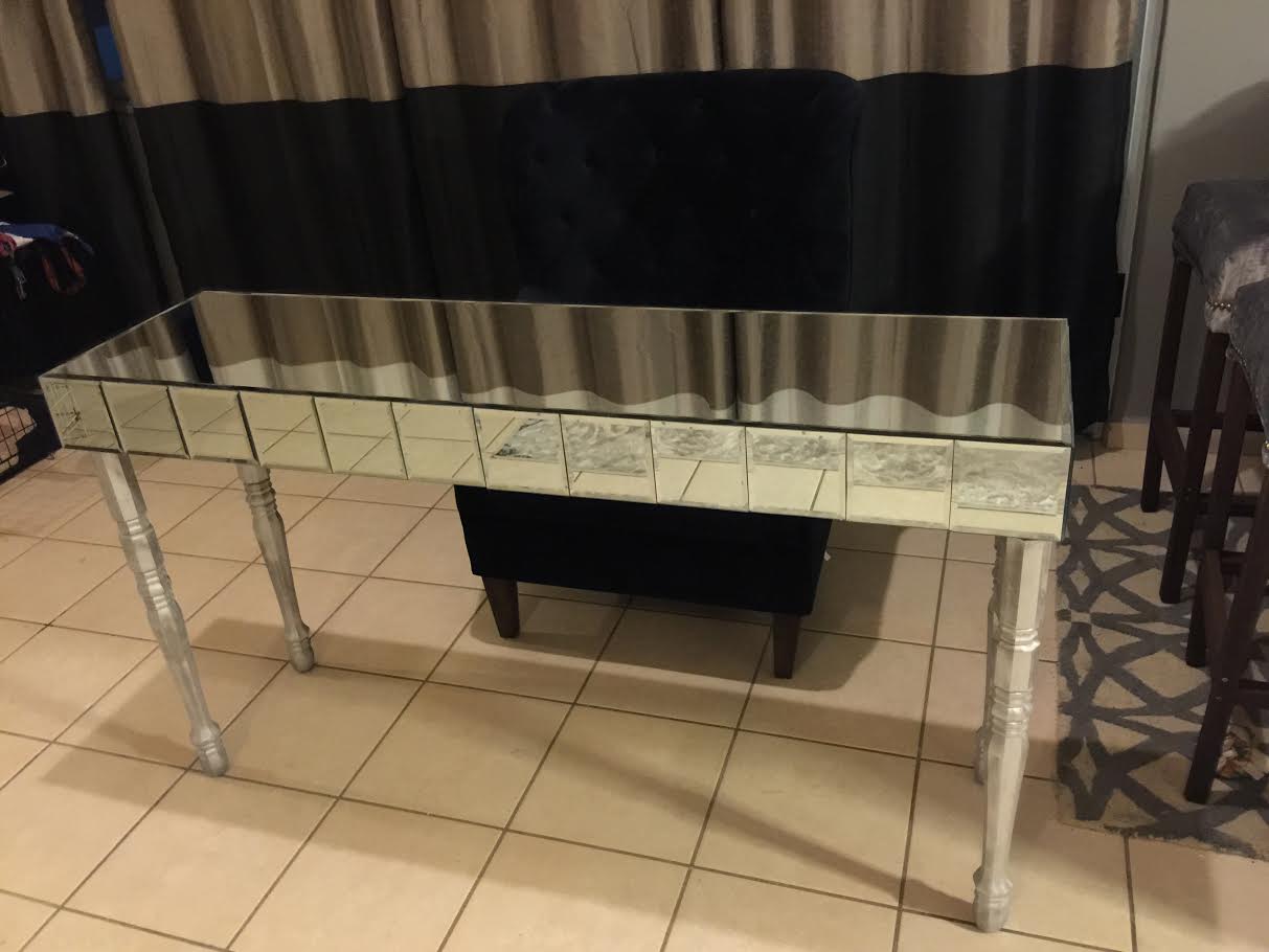 thin, mirrored table with long silver legs