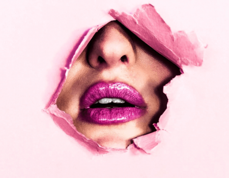 labios rosados sobresaliendo de papel rosado roto en ilustración de cuándo expira el maquillaje
