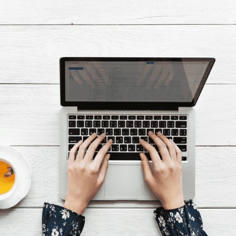 manos femeninas escribiendo sobre teclado de una computadora portátil